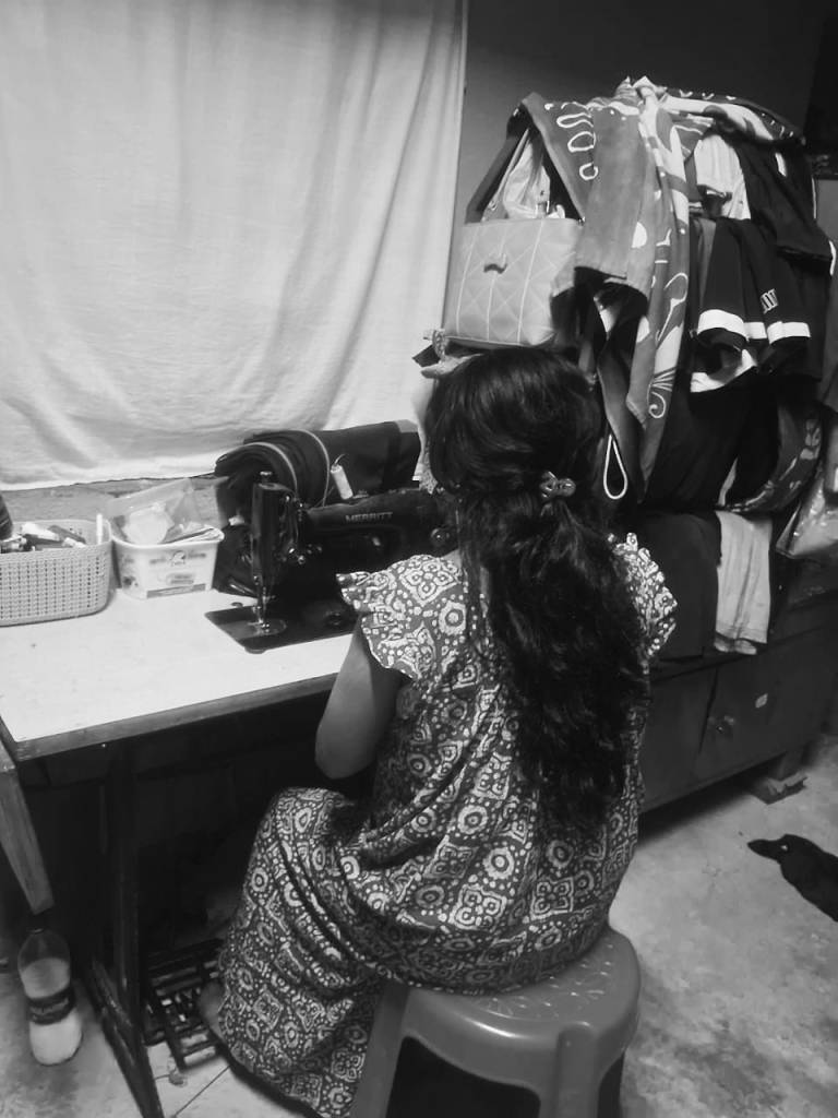 Kavitha working on her sewing machine at her residence